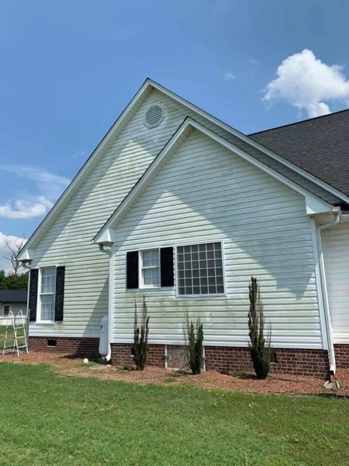 Clean pale siding and brick base on a ranch home after soft washing
