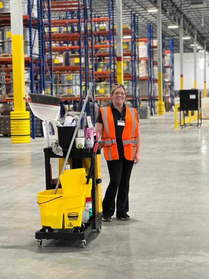A Clayton Pressure Washing team member with a janitorial cart inside a warehouse facility