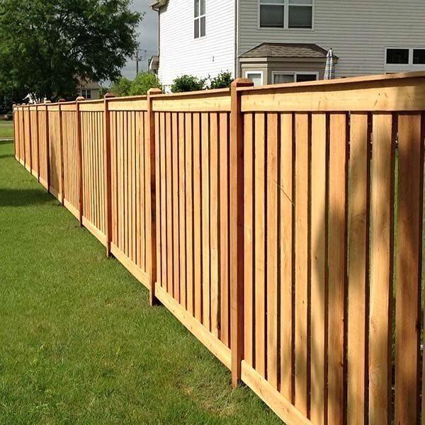 Wood privacy fence running along a lawn after cleaning