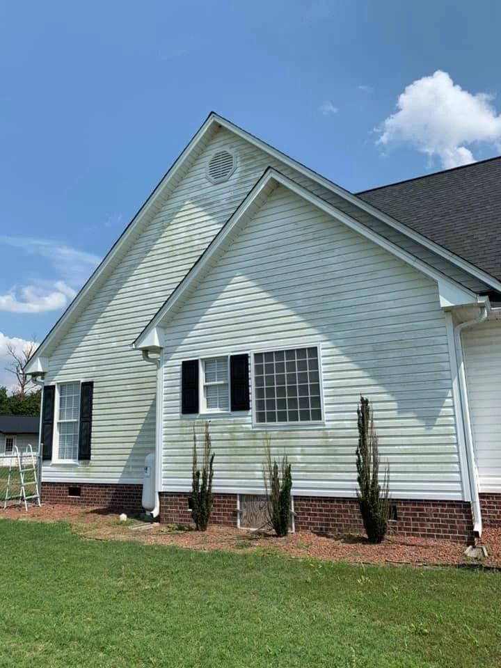 Clean pale siding and brick base on a ranch home after soft washing