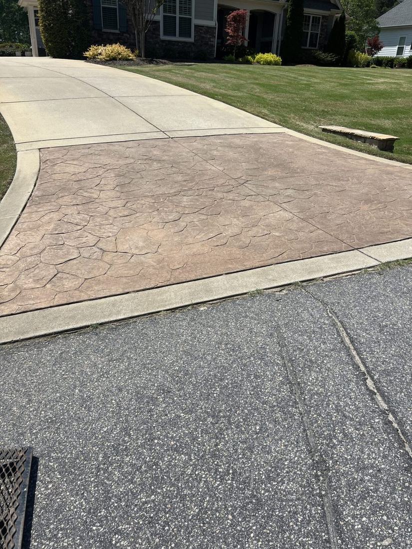 Stamped concrete driveway apron cleaned in front of a suburban home